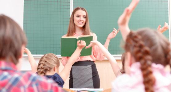 Teacher in front of a classroom holding a book